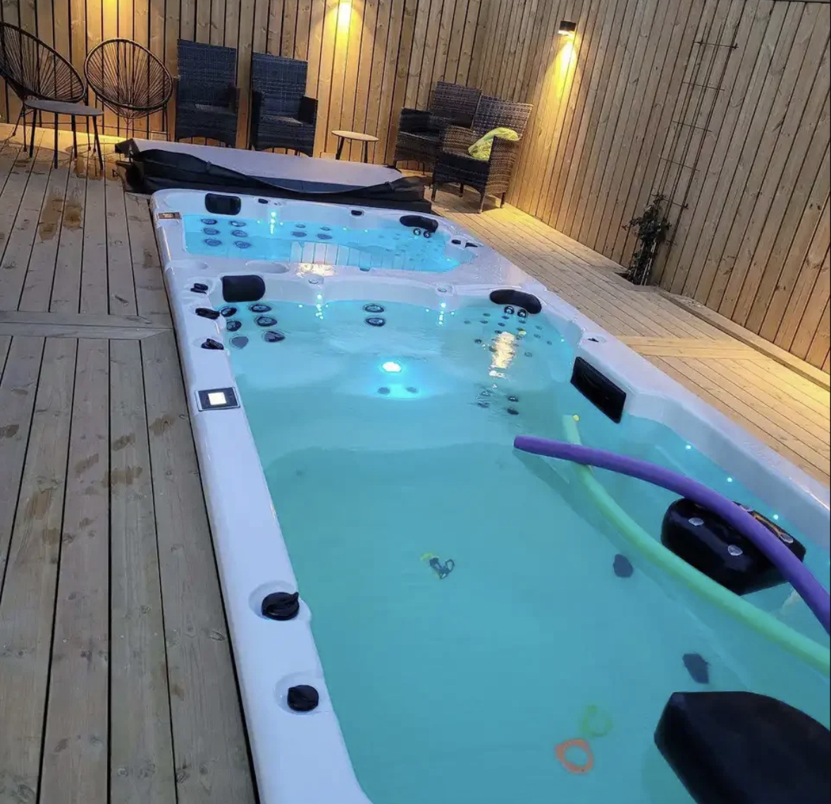 Spa de nage éclairé sur terrasse en bois